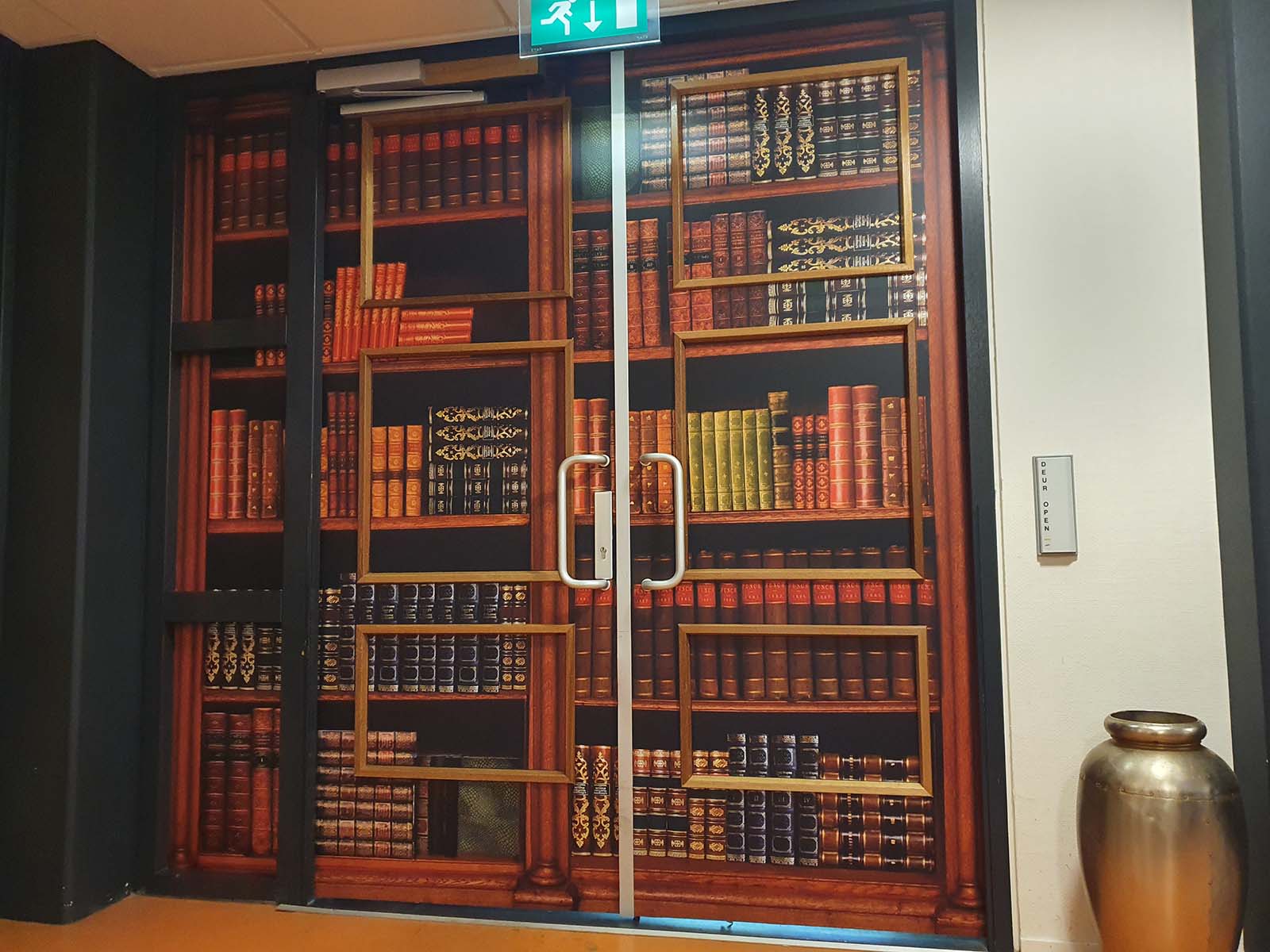 Deurbestickering met boekenkast print zodat de deur uit het zicht onttrokken wordt