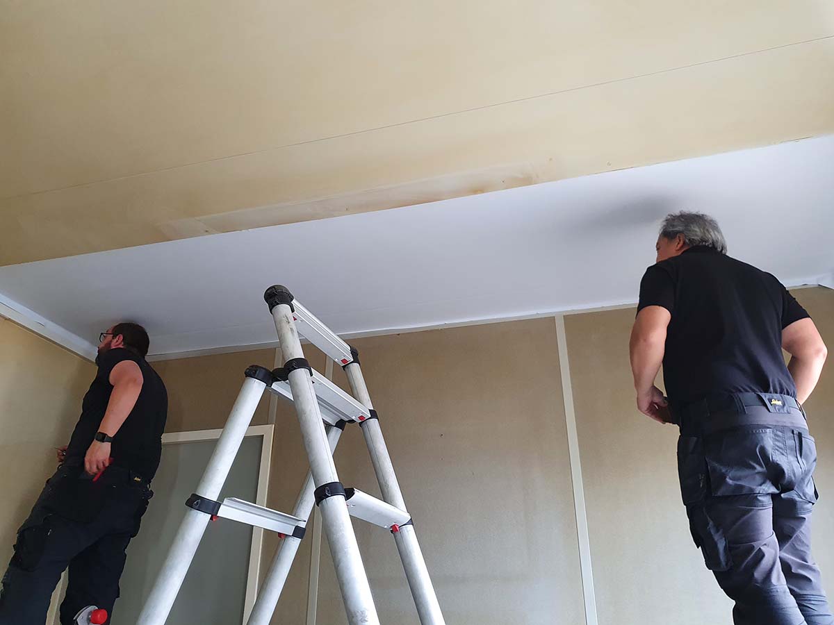 Oud en geel plafond wordt voorzien van een nieuwe frisse kleur met interieurfolie